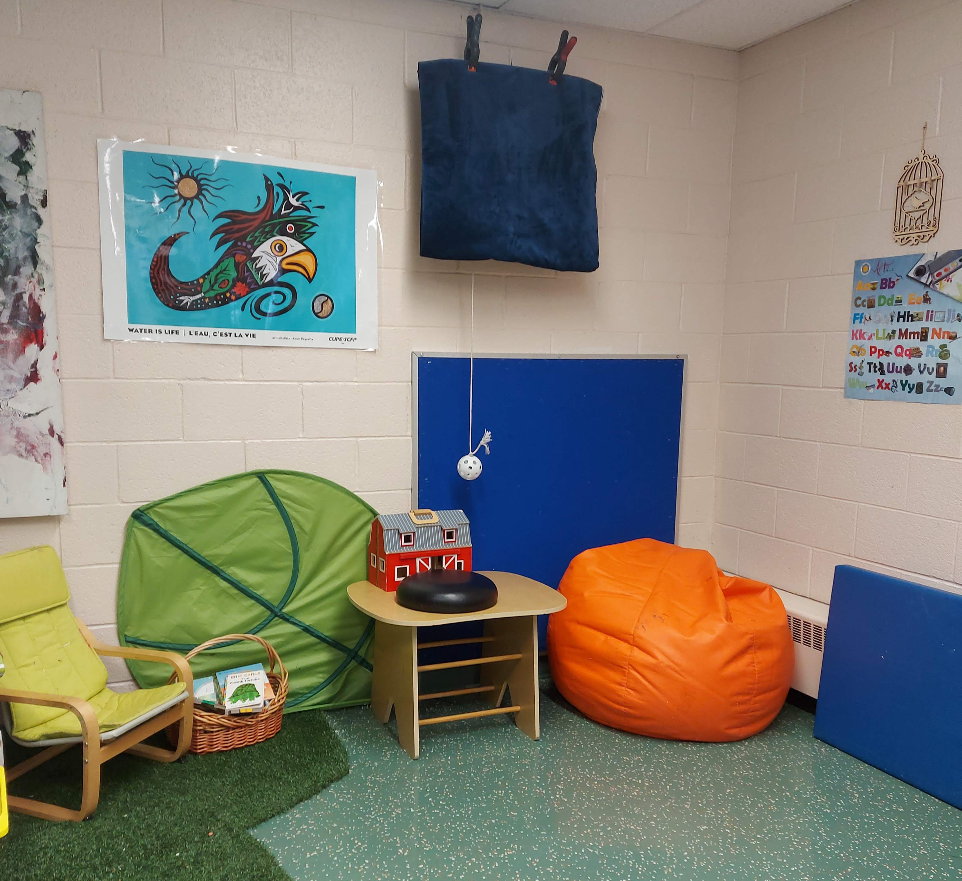 Break time area A corner of a classroom with two bean bags for seating, a smal table, a small chair, and some floor mats a couple of different toys